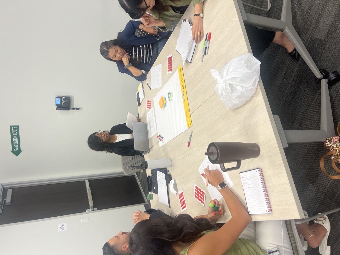 Participants working around a table with paper, markers and red dots