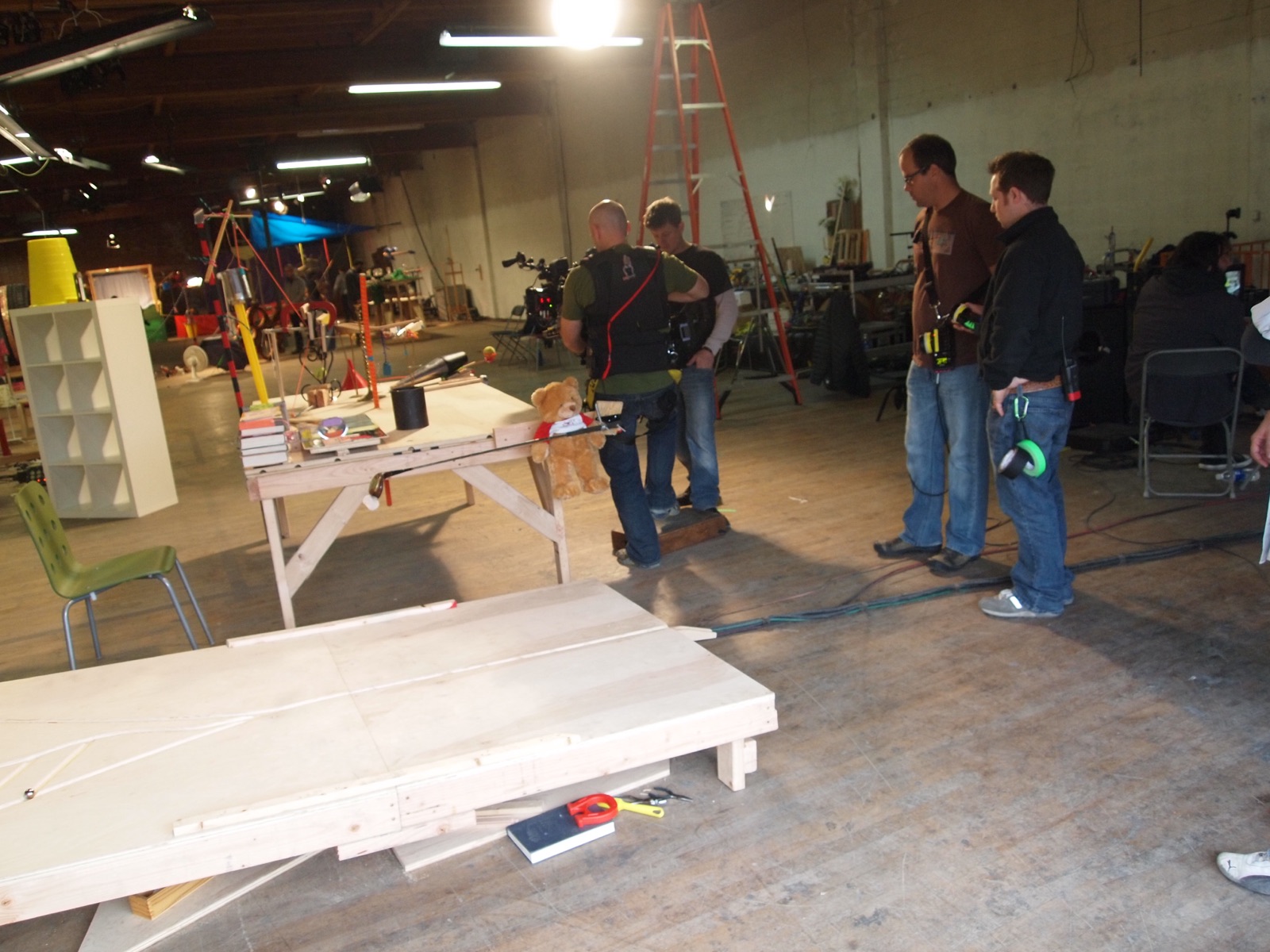 Crew members standing in the warehouse near a work table and stacked boards