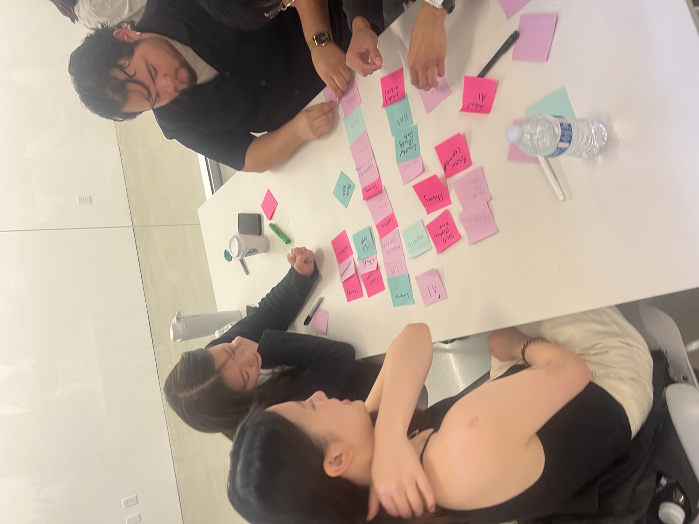 Participants at a table sorting pink and green sticky notes