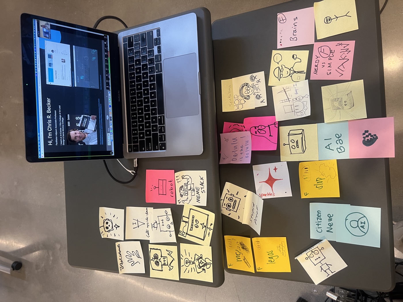 Sticky note icons arranged on a table next to a laptop showing the slides
